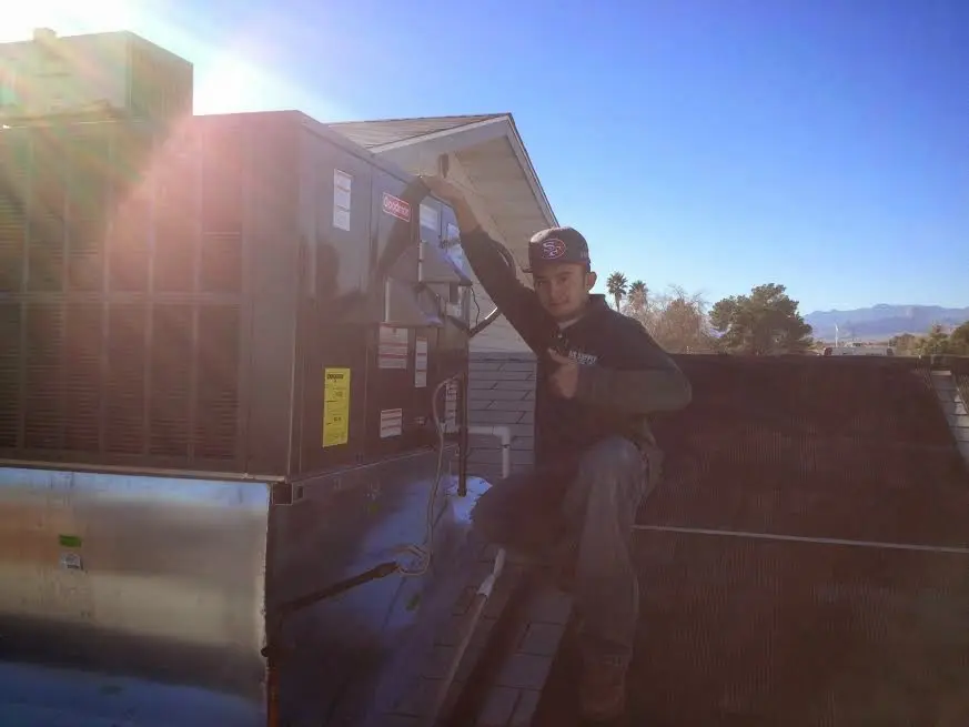 HVAC technician performing Air Duct Cleaning on a rooftop unit in Danville
